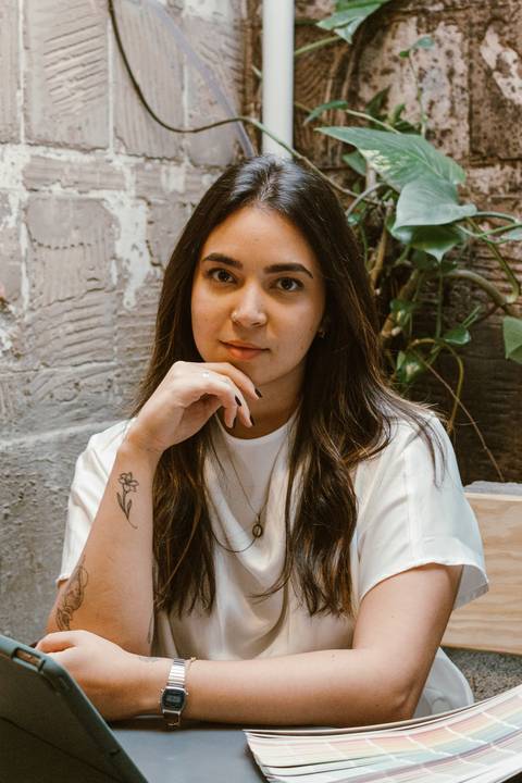 nicole com o braço apoiado na mesa, olhando para mim, séria'