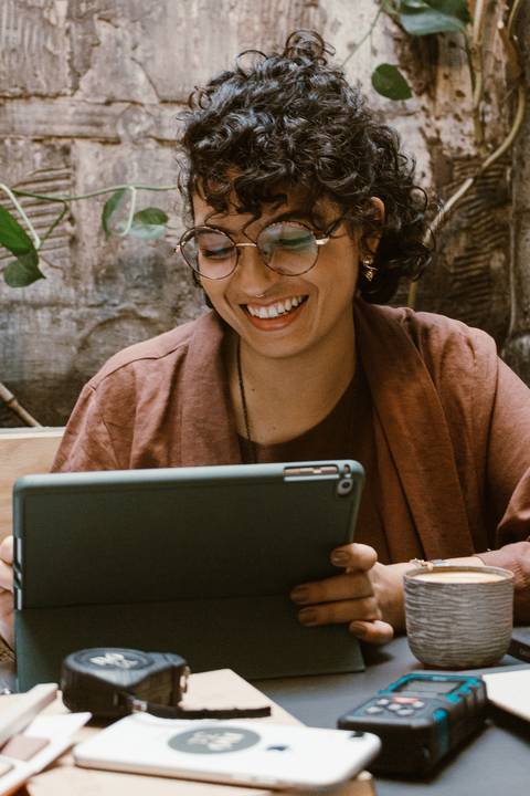 leticia sorrindo, enquanto olha e trabalha em seu tablet'
