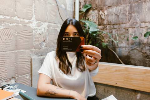 nicole com seu cartão de visita em frente ao rosto, sua marca'