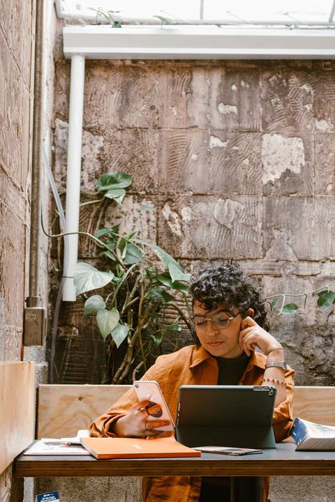 leticia sentada dentro da cafeteria, com o tablet, novo enquadramento, com plantas ao fundo'