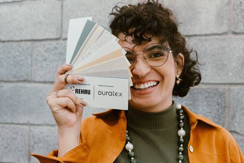 leticia na parte de fora da cafeteria em frente a escadaria, com paleta de cores em frente ao rosto'