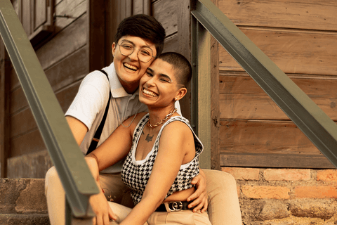 le e mika sentadas nas escadas em frente a uma casa com os rostos colados, sorrindo'