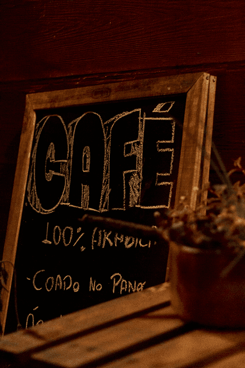 placa de café da cafeteria, com um vaso de flores ao lado'