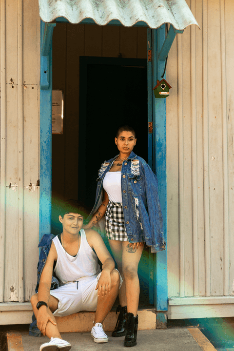le e mika em frente a porta da cafeteria, mika em pé ao lado de le que está sentada no degrau'