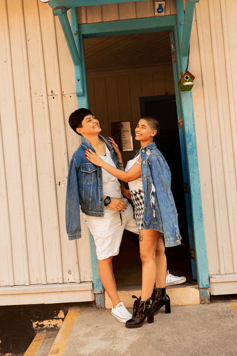 mika e le na porta, em pé, sorrindo, mika com as mãos nos ombros da le'