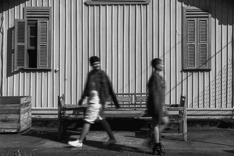 mika e le andando em frente aos bancos de madeira da cafeteria, le olhando para mika'
