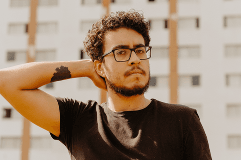 Leo no centro cultural são paulo, prédio de fundo, leo com a mão na cabeça, sério, olhando para a câmera'