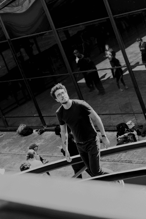 Leo no centro cultural são paulo, subindo as escadas, com um pessoal e vidro de fundo'