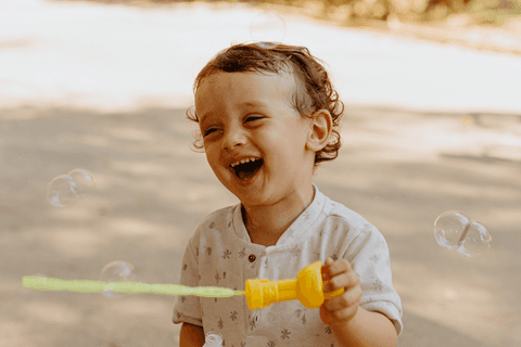 lorenzo sorrindo enquanto brinca fazendo bolhas de sabão'
