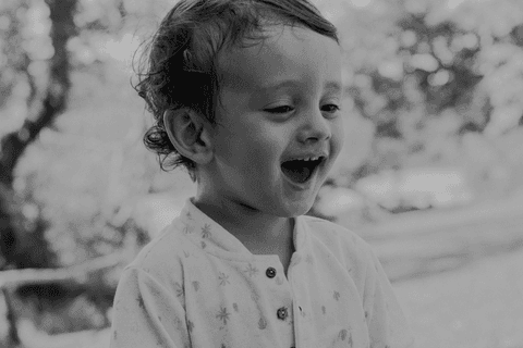 lorenzo sorrindo encantado com a brincadeira, lago e vegetação ao fundo, foto em preto e branco, lolo mega surpreso'