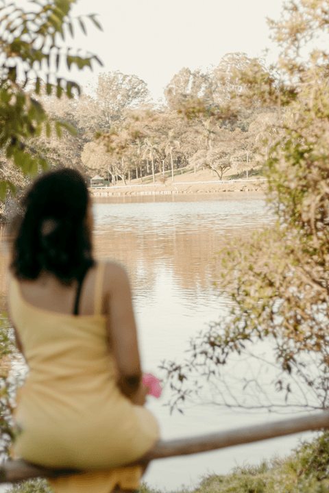leticia sentada no corrimão de madeira no parque do carmo em frente ao lago'