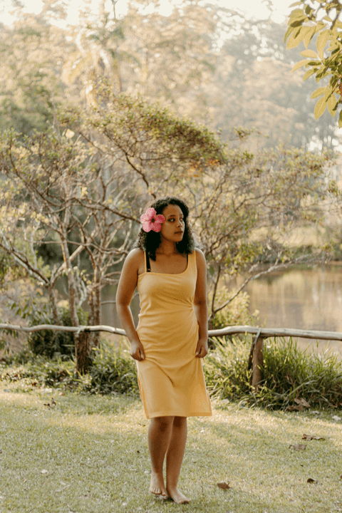 lety caminhando em minha direção em frente ao lago do parque, olhando para o lado, enquanto segura o vestido'
