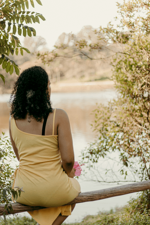leticia sentada no corrimão de madeira no parque do carmo em frente ao lago, fundo desfocado'