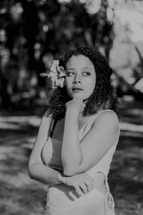 leticia com a mão no queixo, em meio ao campo do parque do carmo, foto em preto e branco'