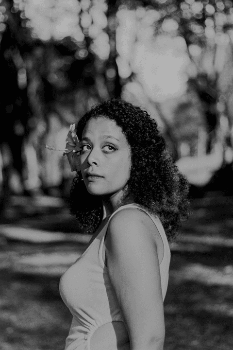 leticia olhando para o horizonte, com a flor em seu cabelo, foto em preto e branco'