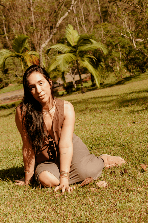 luiza sentada no campo do sesc itaquera, apoiando os dois braços no chão, agora mais séria'