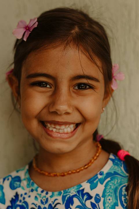 maria com sorrisão, rosto enquadrado na foto, flores em seu cabelo'