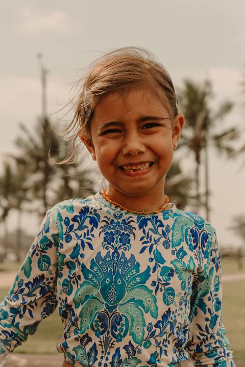 maria sorrindo para a câmera, dia iluminado pelo sol na praia de bertioga'