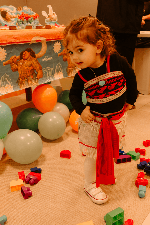 maria eduarda curiosa em frente a mesa do bolo, em pé com as mãos na cintura'