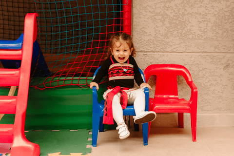 maria se divertindo brincando na cadeira ao lado da casinha de bolinhas'