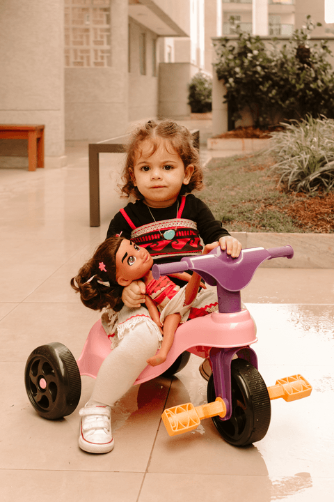 maria mais séria em cima de sua motoca, com a sua boneca da moana'