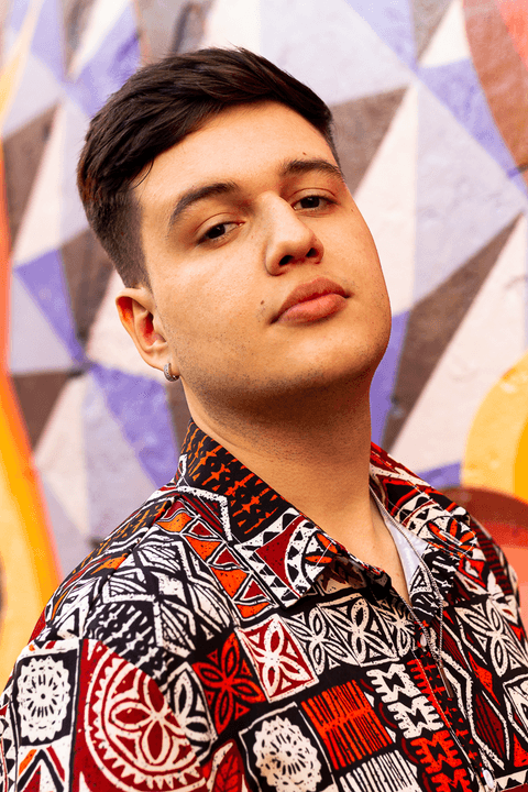 nathan olhando para a câmera, sério, fundo de parede colorido, mais de frente para mim, sem óculos'