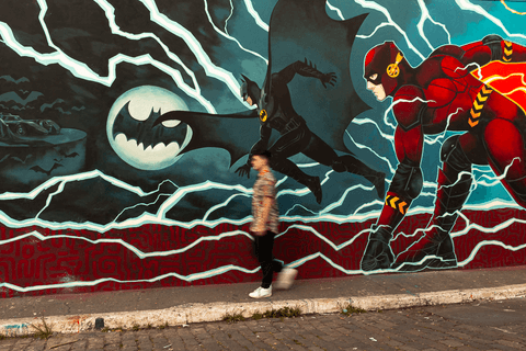 nathan caminhando em frente ao muro com pintura de batman e flash'
