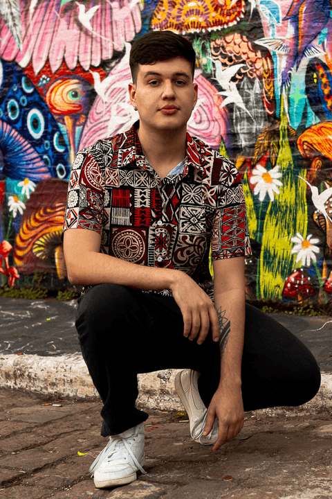 nathan agachado em frente ao muro pintado de grafite, olhando para mim'