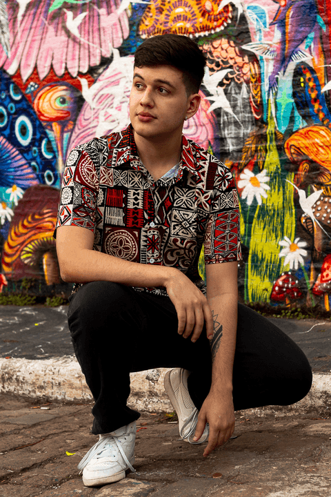 nathan agachado em frente ao muro pintado de grafite, olhando para o lado'