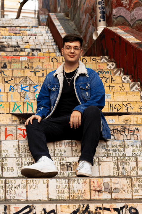 nathan sentado no escadão amarelo, todo grafitado'