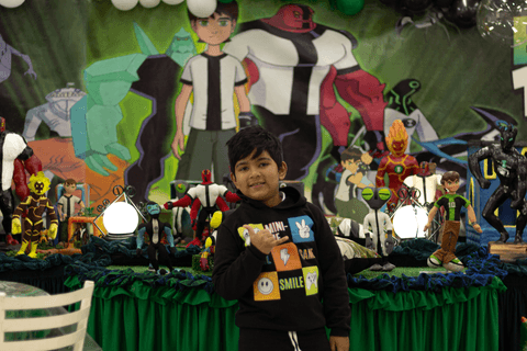 pedro em frente a mesa de decoração com tema do ben 10'
