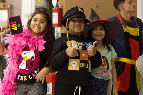 pedro com seus amigos fantasiados dando joinha para a câmera, todos sorrindo, felizes'