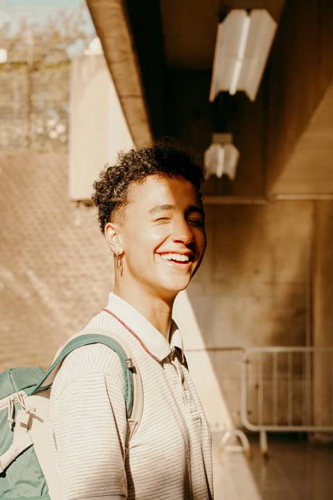 raoni com meio rosto sendo iluminado pela luz do sol, sorrindo, com os olhos fechados'