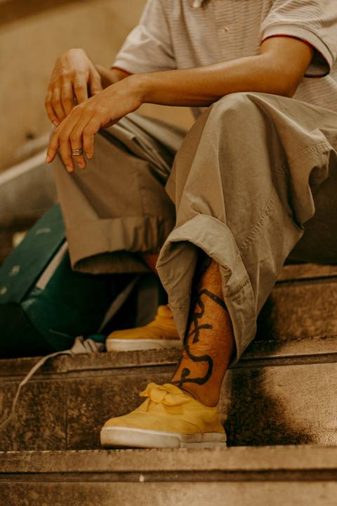 raoni sentado nas escadas da estação da patriarca, linha vermelha do metrô, meio corpo, mostrando sua tatuagem'
