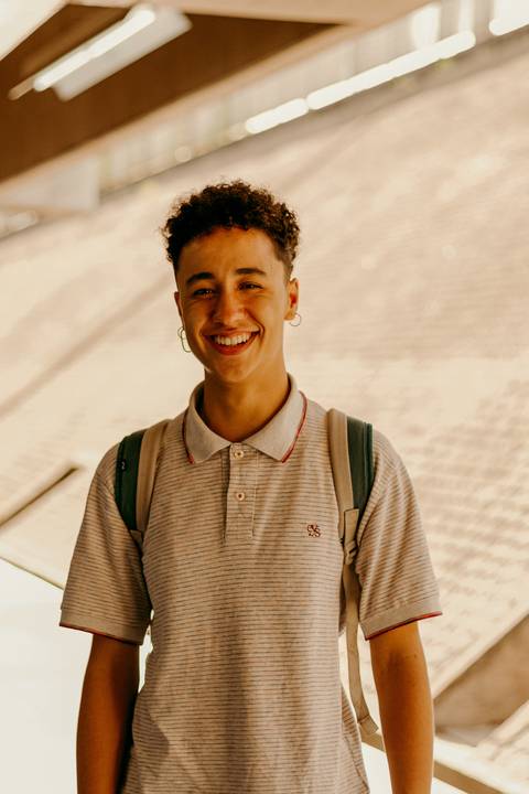 raoni sorrindo, mais próximo de mim, parede de concreto ao fundo'