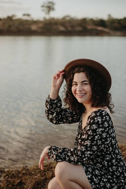 ensaio feminino externo a beira do lago com roupa preta e branca e chapeu marron estilo boho, menina cacheada'