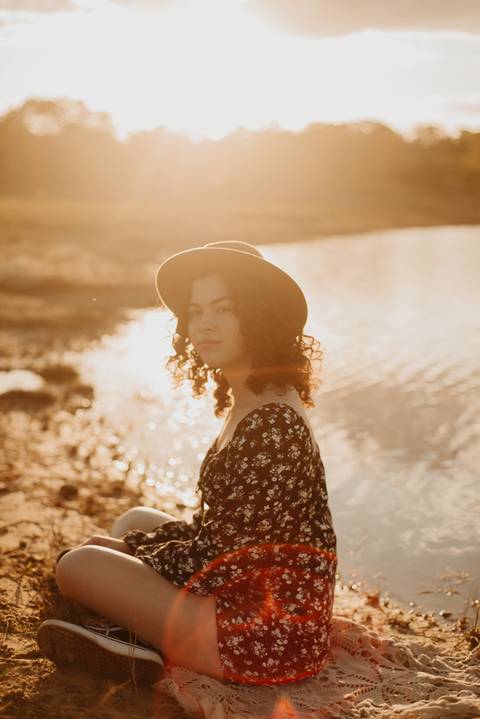 ensaio feminino externo a beira do lago com roupa preta e branca e chapeu marron estilo boho, menina cacheada'