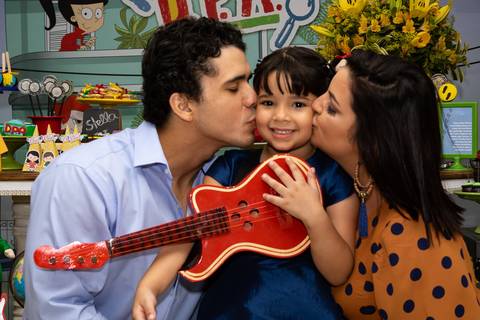 Aniversário Infantil no play, aniversariante recebendo beijo do pai e da mãe'