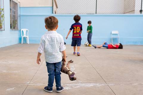 Aniversário no play, Tijuca, meninos jogando futebol e uma criança assistindo segurando um dinossauro'