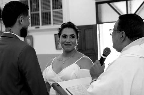 Casamento Religioso durante o dia, Noiva olhando o Padre, Padre falando aos noivos, Noivos diante do Altar'