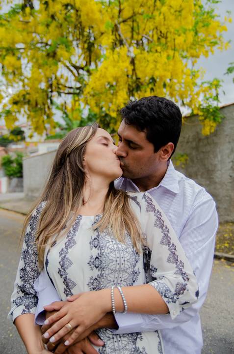 novo casal de beija com árvore florida de amarelo ao fundo'