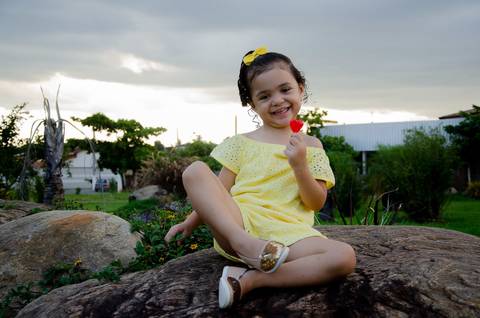 Ensaio pré aniversário de 03 anos - Nicole - Criança de 03 anos em sessão fotográfica - Criança vestindo amarelo sentada sobre uma pedra'