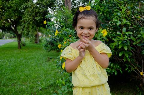 Ensaio pré aniversário de 03 anos - Nicole - Criança de 03 anos em sessão fotográfica - vestindo roupas amarelas com fundo de paisagem natural verde com flores amarelas'