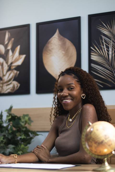 mulher negra em escritório com acessórios de ouro posa para foto'
