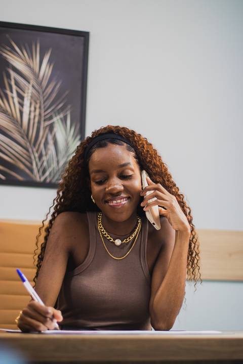 mulher negra empresária fala no telefone em mesa de escritório '