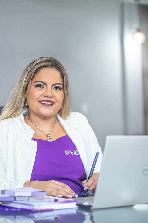 mulher loira de blazer branco e vestido roxo olha para câmera sorrindo'