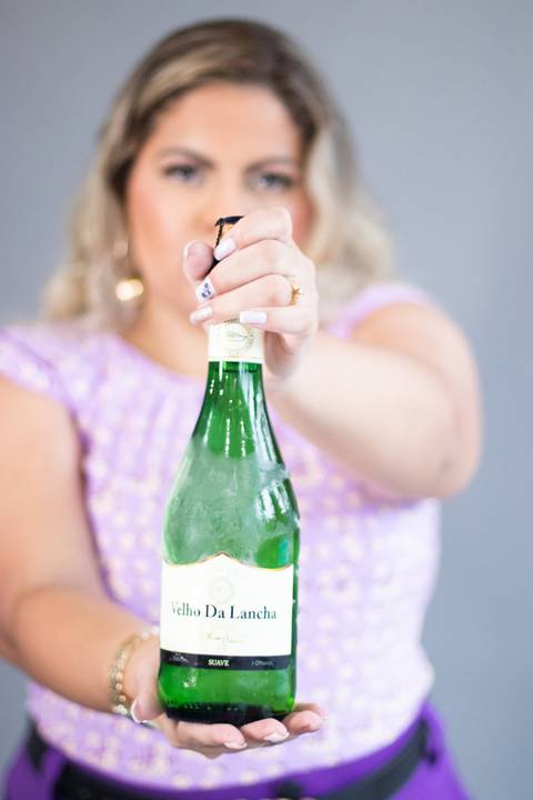 mulher loira desfocada mostra garrafa de vinho '