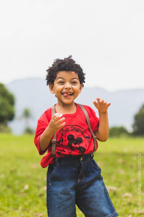 criança de cabelo cacheado posa sorrindo para foto na quinta da bosta vista em ensaio fotográfico infantil '