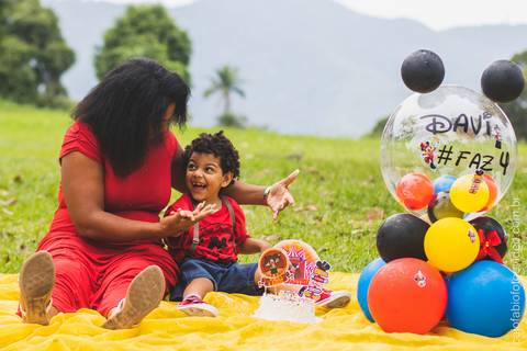 mãe mulher negra com filho pequeno de cabelo cacheado no gramado ensaio fotográfico infantil '