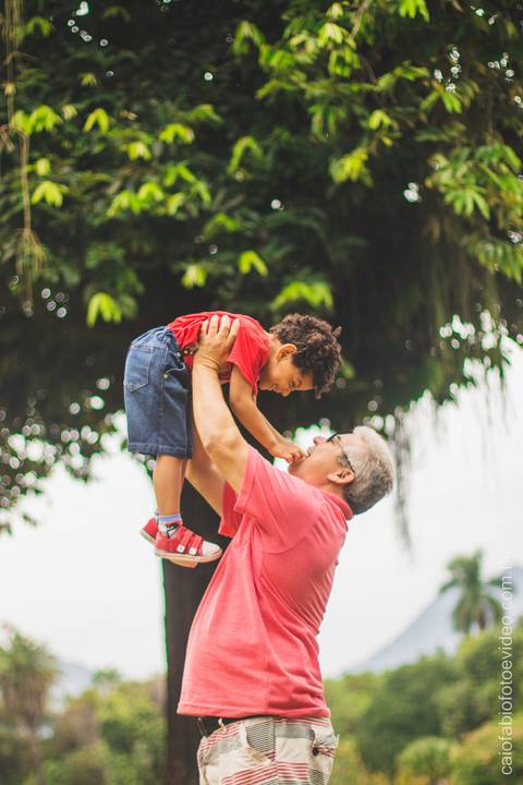 pai levanta filho pequeno brincando em ensaio fotográfico infantil '